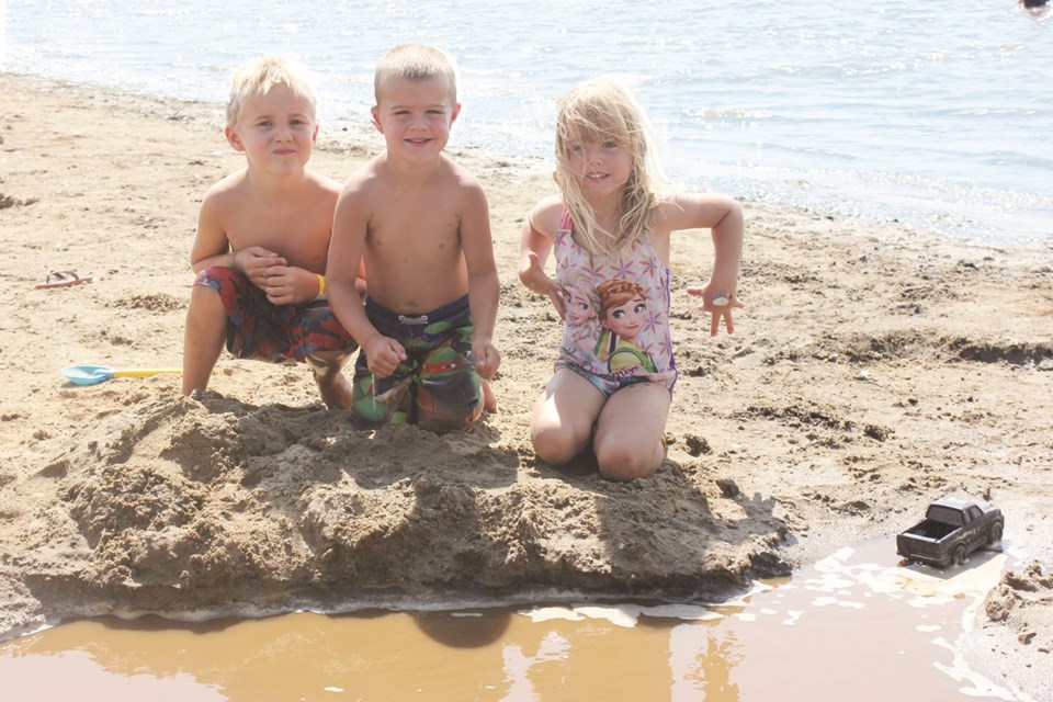 From left, Jackson Kennedy, Kolter Snell and Bailey Abbott create a water channel during Beach Bash in July.