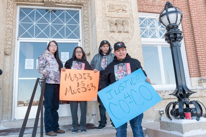 Debbie Baptiste, mother of Colten Boushie, and family hold up signs before entering the courthouse.