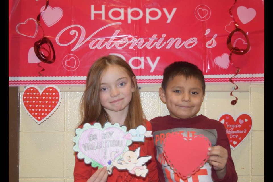 In preparation for St. Valentine’s Day which is being celebrated next week, Kaley Allard and Stefan Gamble, students in Chelsey Williams’ Grade 1 class at Victoria School, agreed to exchange valentines in front of a colourful mural decorated with hearts.