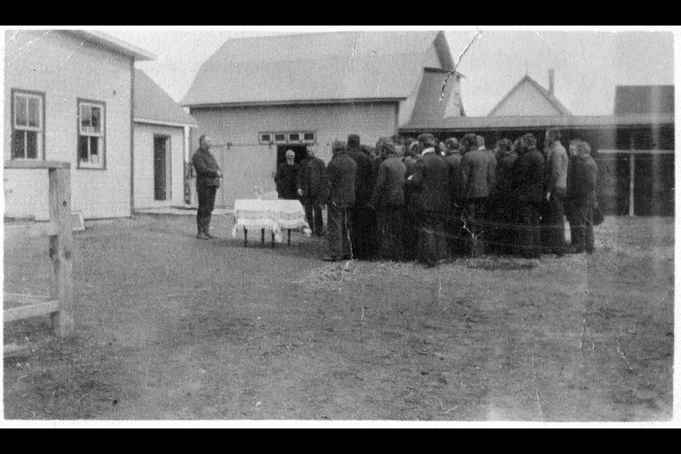 Local Doukhobors held an open-air moleniye (prayer meeting) in the courtyard between the dwelling house (left) and the trading store. Note the barn and drive shed in background, 1912. ----Photo courtesy Fred Dergousoff.