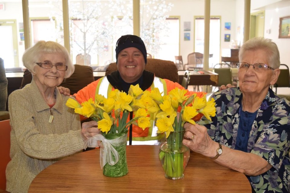 The Kamsack Volunteer Firefighters Association donated the money to purchase 13 bundles of daffodil blooms from the Hiawatha Chapter of the Eastern Star at Kamsack to Eaglestone Lodge. Photographed with a couple bouquets of the yellow blooms, which were sold as a fundraiser for the Canadian Cancer Society, from left, were: Shirley Moore, a member of the Eastern Star; Darcy Green, a firefighter, and Stella Matsalla, a resident.