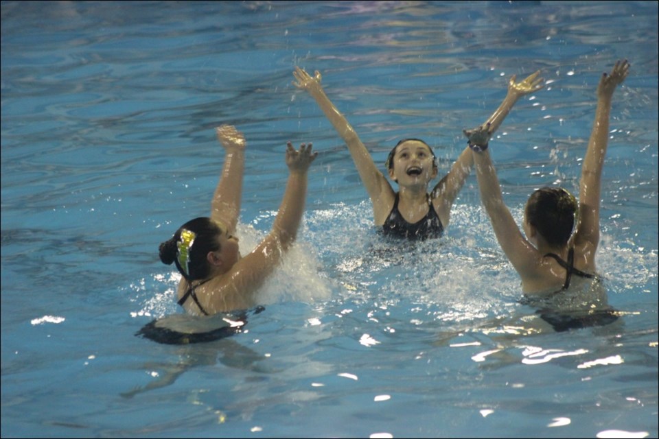 Mattie Clarke, Mackenzie McLean and Parker Ledoux put a final flourish on their routine at the Flin Flon Aqua Doves water show on April 19. - PHOTO BY ERIC WESTHAVER
