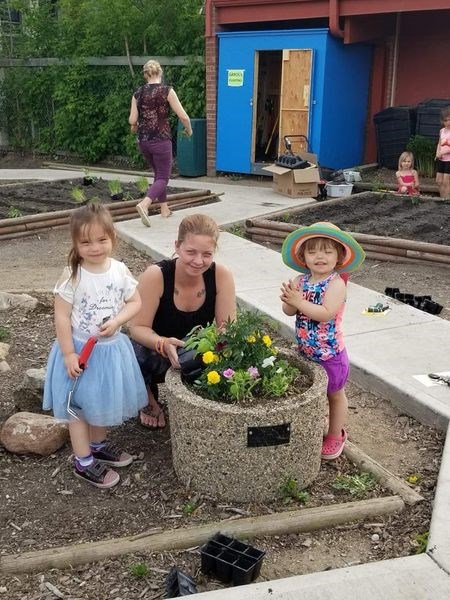 Zophya Gouge, left, had help from her mother, Brittney Durell and sister Zahara Gouge, planting flowers at Victoria School on Family Fun Night.