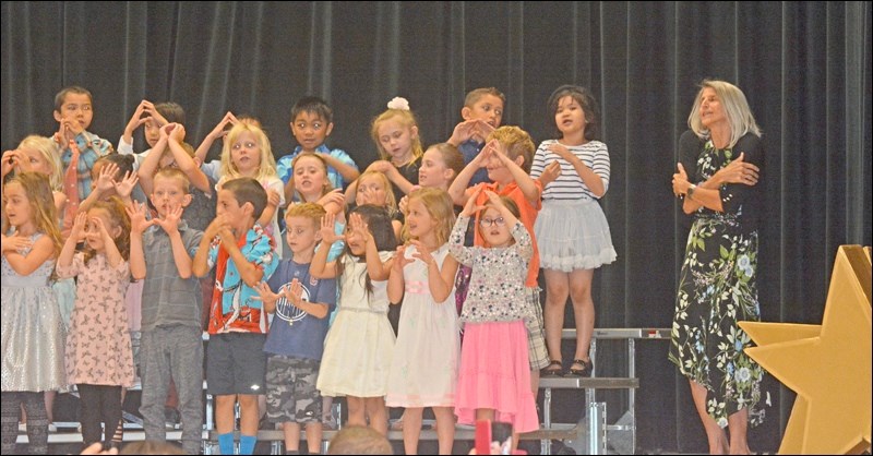 Mmes. Natalie Jesney and Laurette Koshman presented certificates to kindergarten students who were moving into grade 1. Pictured here is Mme. Koshman directing the students as they sing Nous sommes tous comme les fleurs, French for “we are all like flowers.”