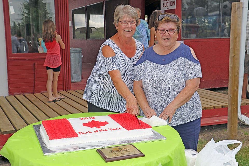 Barb Pickering and Susan Schroepfer cut the Canada Day cake at the celebration at Pasuqia Regional Park. The park was declared the province's park of the year earlier in the season. Photo by Devan C. Tasa