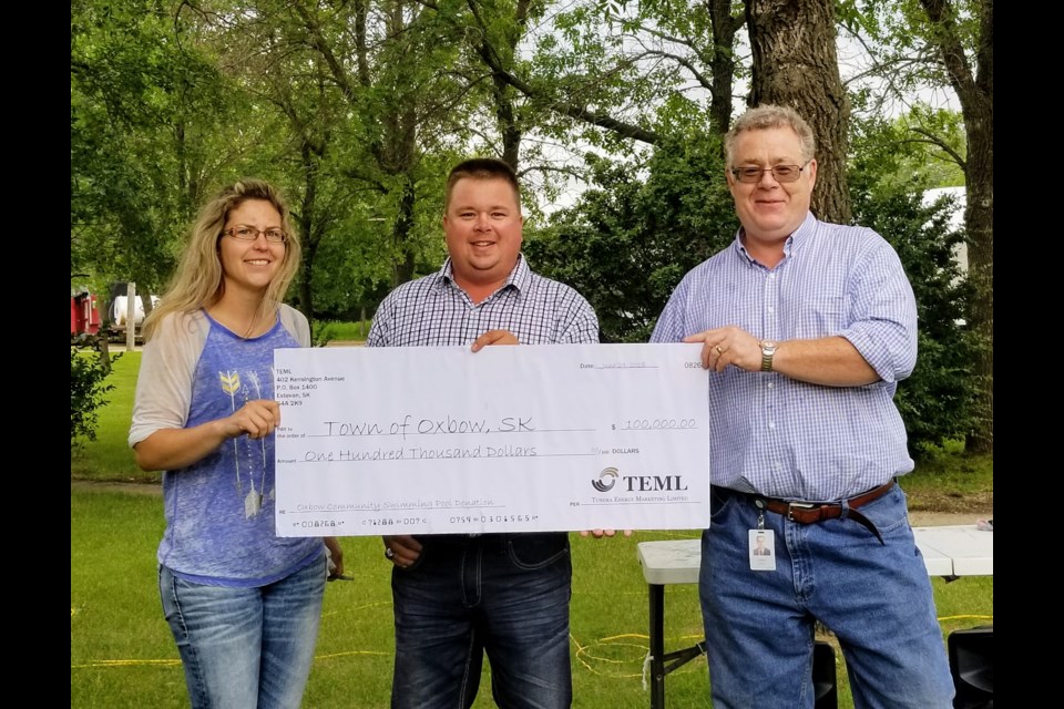 TEML vice president of operations John Williams, right, and Bryce Merkley, field operator 2 with TEML, centre, presented a cheque for $100,000 to Jen Buchanan, left, of the Oxbow swimming pool committee on June 29.