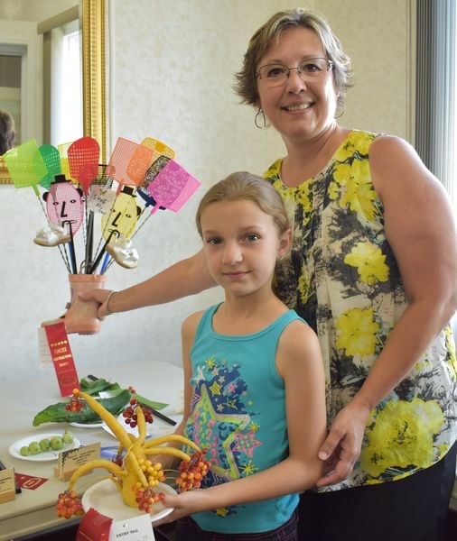 Eight-year old Taylor Thurlow showed off her favorite exhibit, a double-first prize winner called “funky bouquet,” one of 13 items she had entered in the horticulture show on August 10. Beside her is her grandmother Patty Witzko holding another of Thurlow’s entries, a first-prize winner in the decorated garden ornament category titled Shoo Fly Shoe.