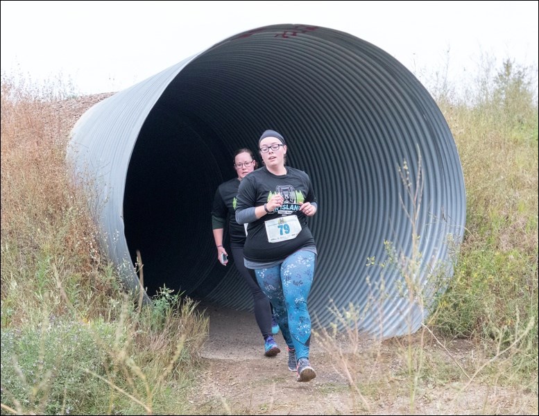 Dani WIlliams of North Battleford comes through the culvert on the other side of highway on way to finishing the 5km run. Photos by Averil Hall