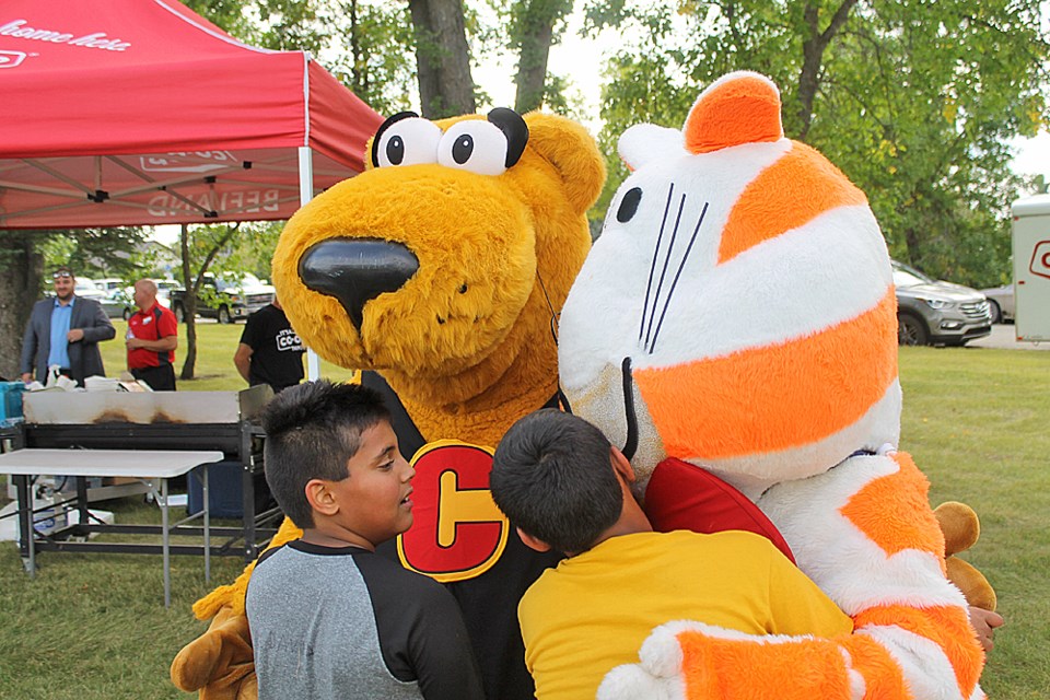 From left, Rajveer Pabla hugging Cooper the Dog, while Nabav Pabla hugs Fat Cat at the birthday party for the Beeland Co-op and Cornerstone Credit Union mascots. The event happened on August 29, after being postponed a day from the weather. Photo by Jessica R. Durling