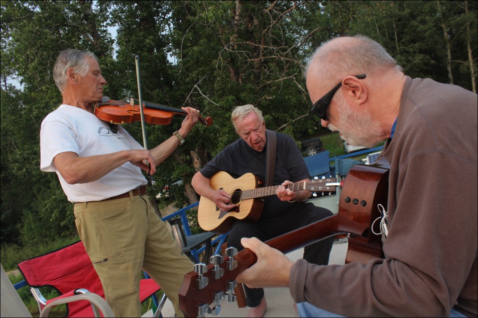 Alistair Callegari, Murray MacDonald and Dave Clement work on a tune during a jam session on MacDonald’s houseboat on Aug. 17. - PHOTO BY ERIC WESTHAVER