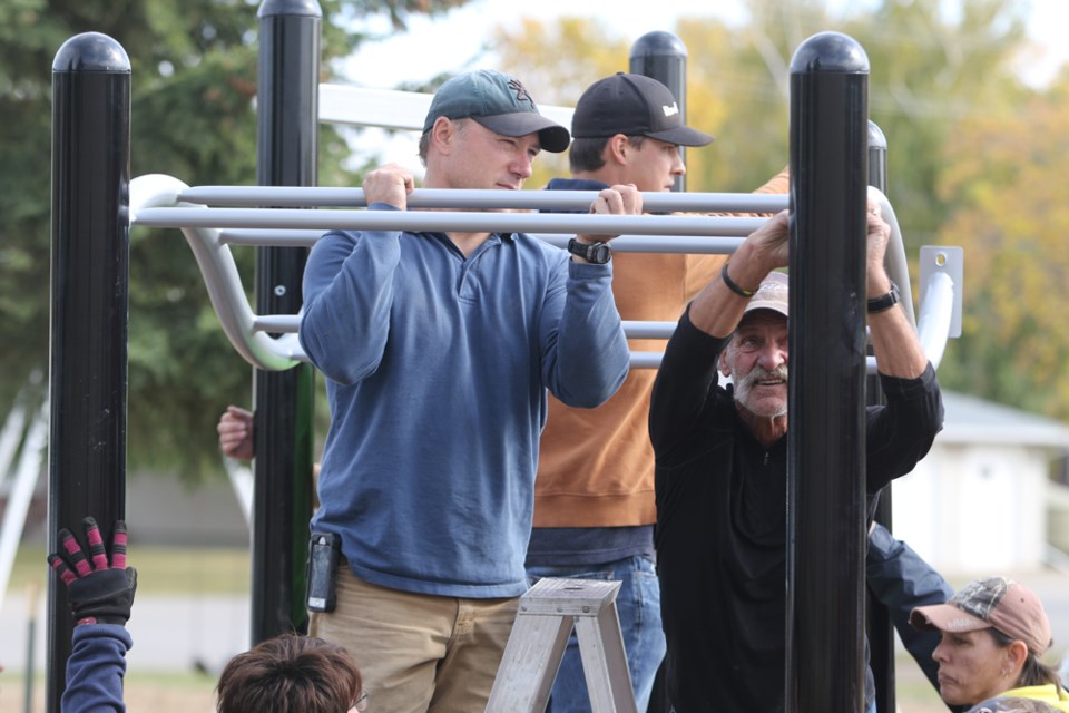 Humboldt's St. Dominic School installed their new playground Sept 12. In this photo, Todd Engle, left, and Don Schlitz, right, hold up the frame for a new set of bars. Behind them, in the brown sweater, is Steven Schreiner. Photo by Devan C. Tasa