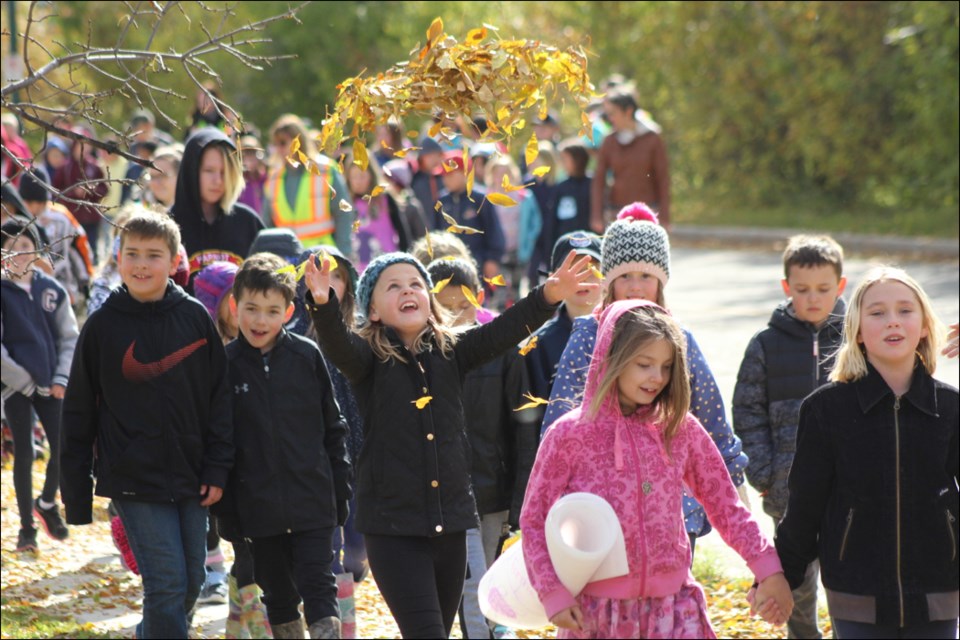 Lydia Alexander tosses an armful of leaves during the École McIsaac School Terry Fox Walk on Sept. 21. All K-8 students took part in the walk, which the school holds each year to raise money for cancer research and promote health. - PHOTO BY ERIC WESTHAVER