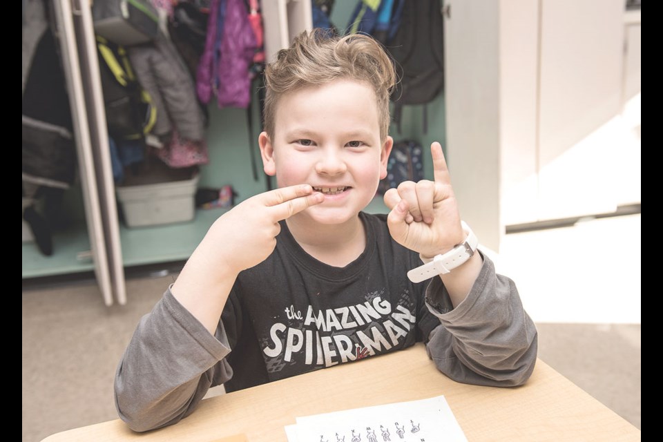 Grade 4 student Kevin-Dean Folk practises his sign language letters. Photo by Chantal Rasmuson