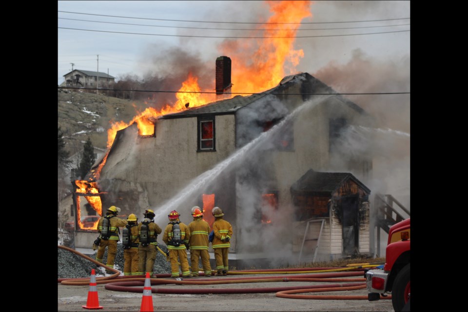 Flin Flon Fire Department members spray down a fire at a building on Island Drive during a training exercise on Oct. 20. Firefighters used new techniques, training and equipment to extinguish the building, which was donated to the fire department. No injuries or damage to nearby homes was reported. The building was destroyed. - PHOTO BY ERIC WESTHAVER