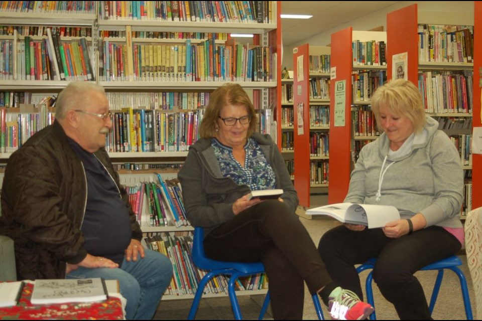 Russel Worobetz, left, explained his book to avid readers during library week at the Preeceville Library, from left, were: Worobetz, Sharon Prystay and Jean Wade.