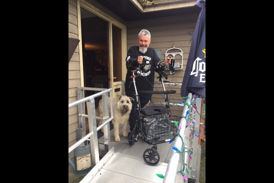 John Sayer tests out his new leg and walker at his home in south Richmond, along with his dog, Dexter.