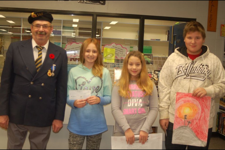 Jim Ward of the Preeceville Legion presented Preeceville School Grade 6 students with prizes for their colour poster in the Remembrance Day contest. From left, were: Ward, Emerson Strykowski (first), Carley Walker (second) and Zachary Delawski (third.)