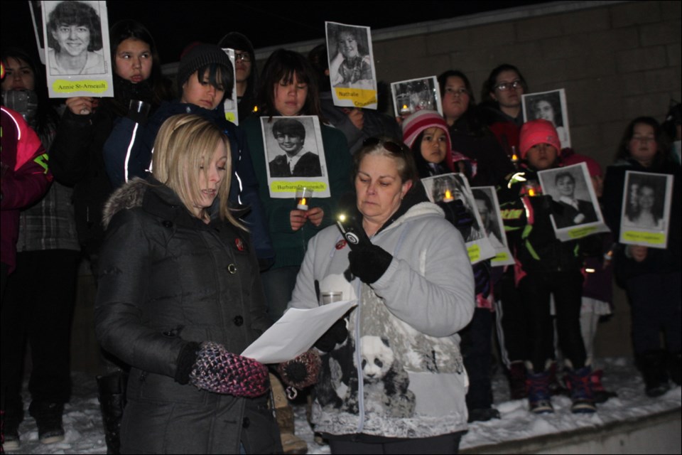 Keely Patterson and Laurie Sealey speak during a candlelight vigil at Pioneer Square on the anniversary of the Montreal massacre Dec. 6. Behind them, members of the Flin Flon Aboriginal Friendship Centre youth group (including Janay Custer and Charlie Custer, right) hold up candles and pictures of the victims. - PHOTO BY ERIC WESTHAVER