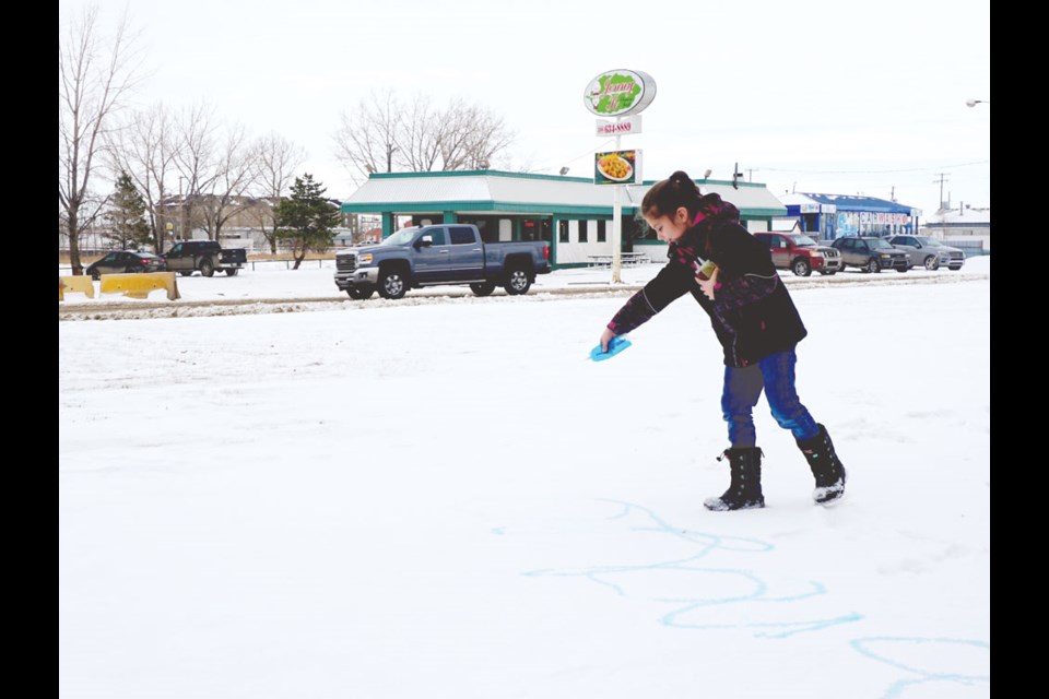 Braya Prybylski painting her name on the snow.