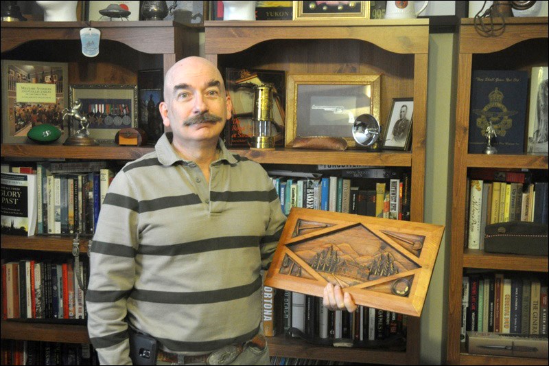 Tim Popp holds a carving made by a miner. Miners carve wood during their off time, Popp said. In addition to being a reserve constable with the RCMP and being involved with the Battleford Legion, Popp researches topics relating to the Yukon, including its military history.