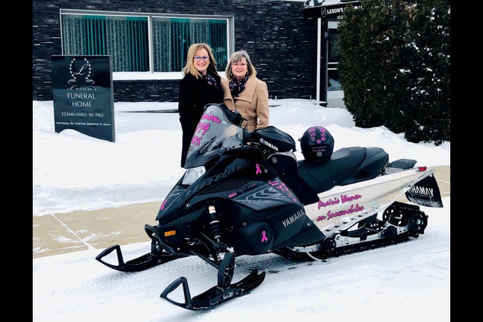 Lois Schlosser, president of Remco Memorials of Regina (right), presented a donation of $3,000 to PWOS (Prairie Women on Snowmobiles) core rider Shawna Leson of Canora on January 11, and got a close look at the snowmobile Leson will be riding during PWOS Mission 2019, scheduled for February 3 to 8.