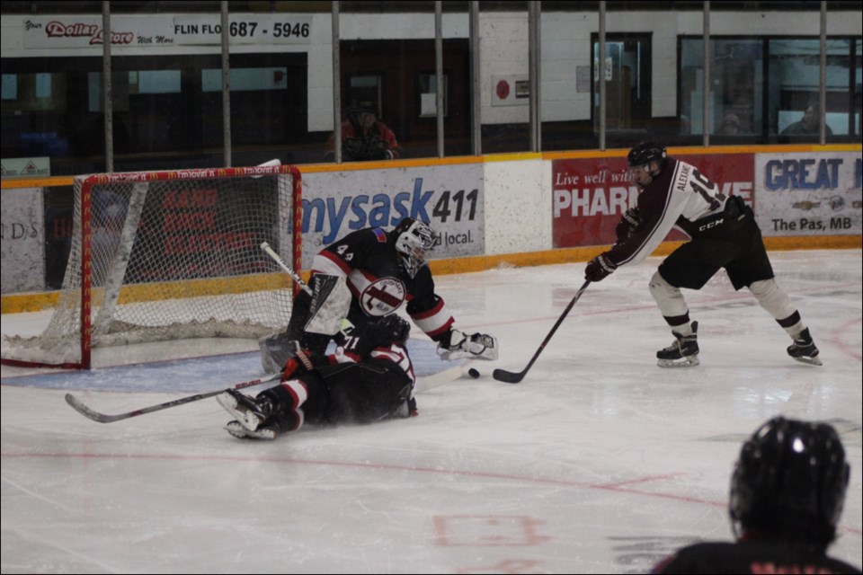 Cross Lake Islanders Ethan Halcrow and Marcus Ross try to keep Flin Flon Midget AA Bomber Blake Alexander from getting to a loose puck. - PHOTO BY ERIC WESTHAVER