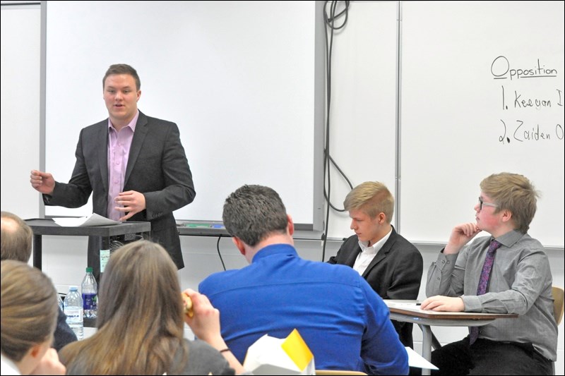 Taegen Isaac (standing) argues in favour of the proposition. Seated are his opposition, Keegan Isaac and Zaiden Osicki.