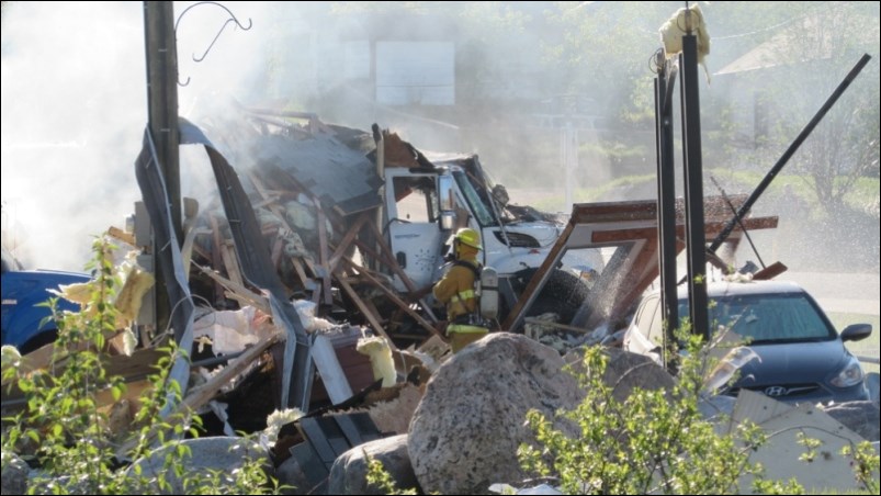 Firefighters spray down debris following a propane explosion at Stittco Energy Limited in May 2016. - FILE PHOTO