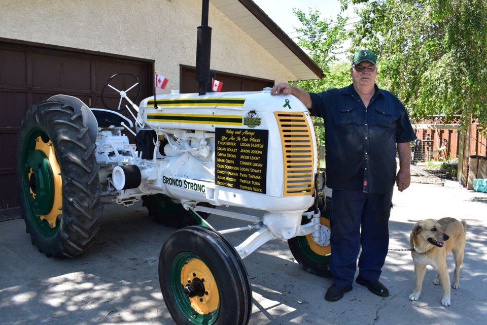 Larry Larson, accompanied by his dog Daisy, stood beside the 1947 Cockshutt 30 tractor which he had restored, and then had painted as a tribute to the Humboldt Broncos hockey team.