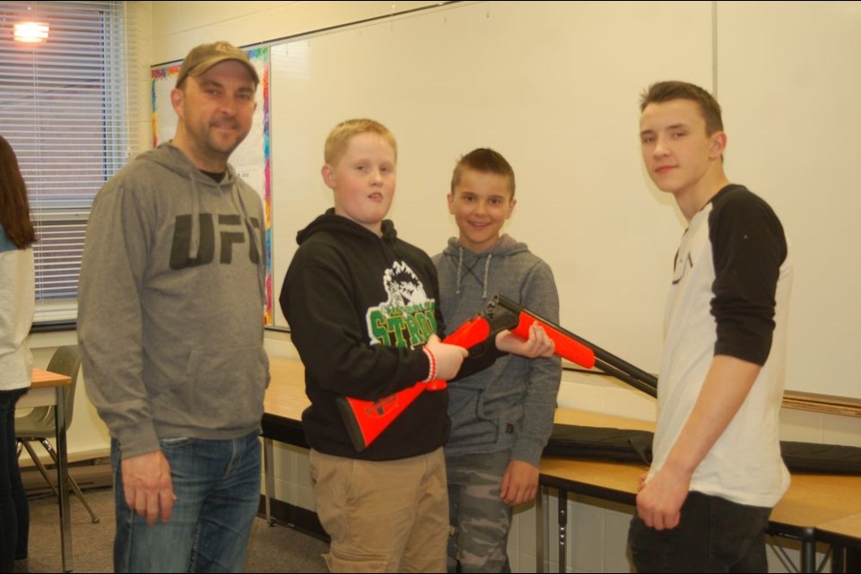 Kelly Masley, volunteer, displayed some of the different types of firearms to students participating in the firearm safety course sponsored by the Preeceville branch of the Saskatchewan Wildlife Federation. From left, were: Masley, Mason Babiuk, Cole Masley and Brett Smith