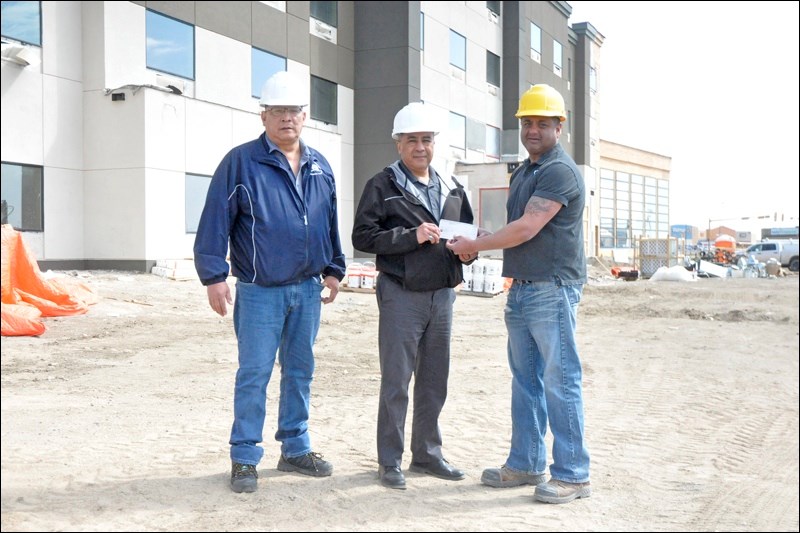 Gary Brar (right), owner of the new Holiday Inn Express and Suites Hotel being built in North Battleford, presents a cheque for $1,000 to Paul Leoux (centre) and Grant Beaudry (left) of Saskatchewan Indian Institute of Technologies Career Centre, in appreciation of the labour that was supplied for the construction. Photos by John Cairns