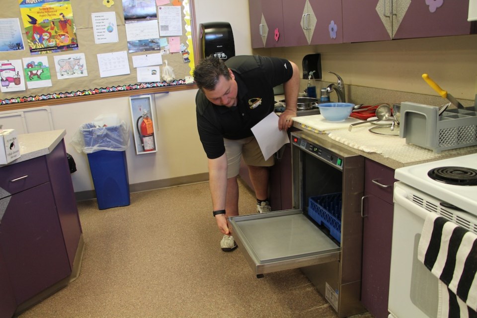 Principal Jason Gordon demonstrates Dr. Brass School's new commercial dishwasher.