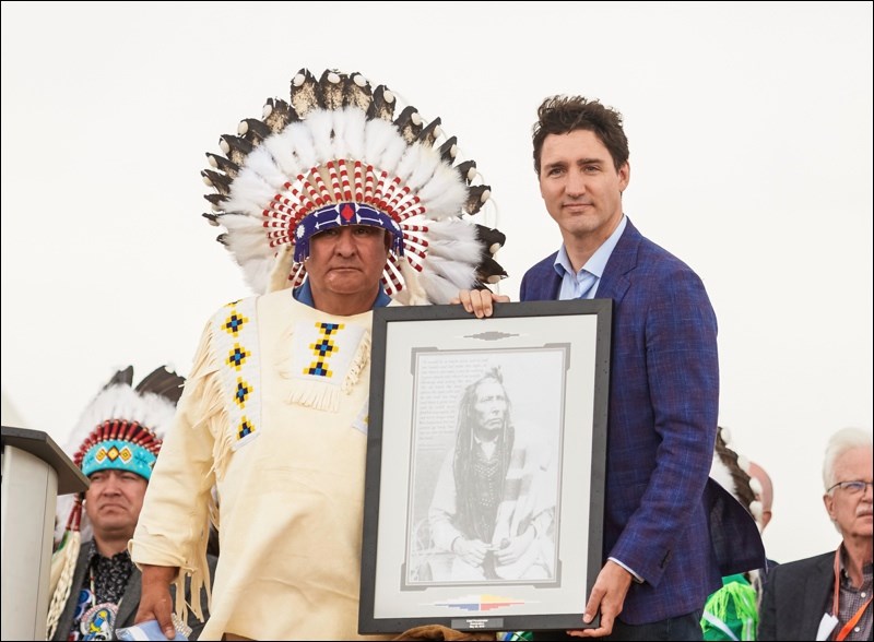 Poundmaker Chief Duane Antoine along with Prime Minister Justin Trudeau holding a photo of Chief Poundmaker.
