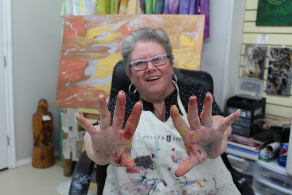 HAPPY HANDS Lynn Burroughs shows off her hands at NorVA Night. She was using mixed acrylic paint to create art on records. - PHOTO BY CASSIDY DANKOCHIK