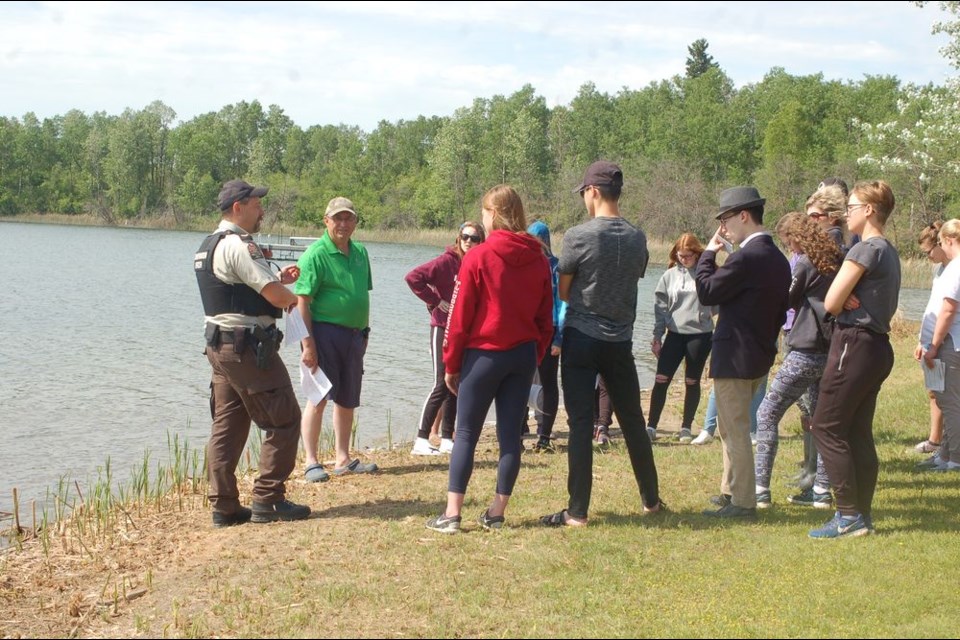 Johnny Petryshyn, left, Saskatchewan Wildlife conservation officer from Preeceville and Ken Somogyi, Provincial Fisheries chairman, explained to a group of students from Melville the importance of featuring the Rainbow Trout fish prior to being released into Lady Lake on June 14.