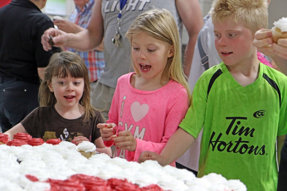 Eden, Lorelei and Micah Funk dive in for some Canada Day cupcakes.