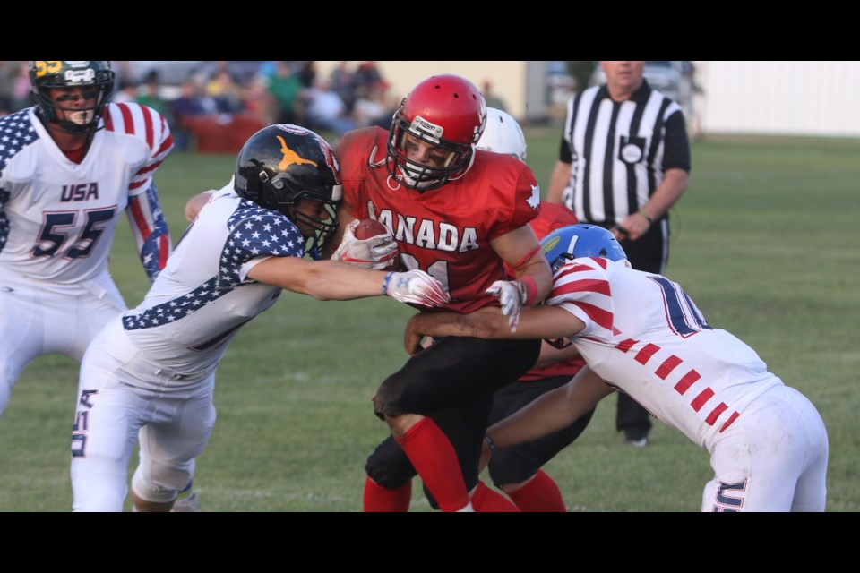 Dalmeny's Thomas Neudorf advances with the ball as the Americans tackle him during the Can Am Bowl in Wakaw on July 6. Photo by Devan C. Tasa