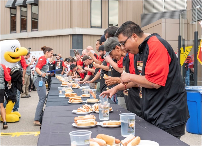 A long line of contestants doing their best to eat the most hot dogs.