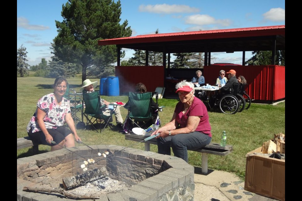 At left, Patty Witzko, activity worker and Adeline Nykolaishen, volunteer helper, roasted marshmallows for all to enjoy during the KDNK annual picnic at Broda Park.