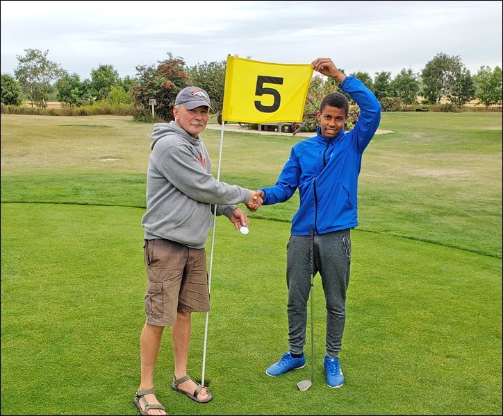Matteo Miedema receiving a free golf pass and hole in one keychain from owner Victor Liebaert.