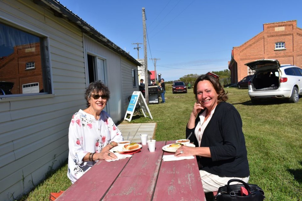 Myrna Dey, left, and Debbie Mandzuk enjoyed the sunny weather at the Kamsack Power House Museum Harvest Time event, sitting at a picnic table with their brunch of “loaded hotdogs and tasty chili.”