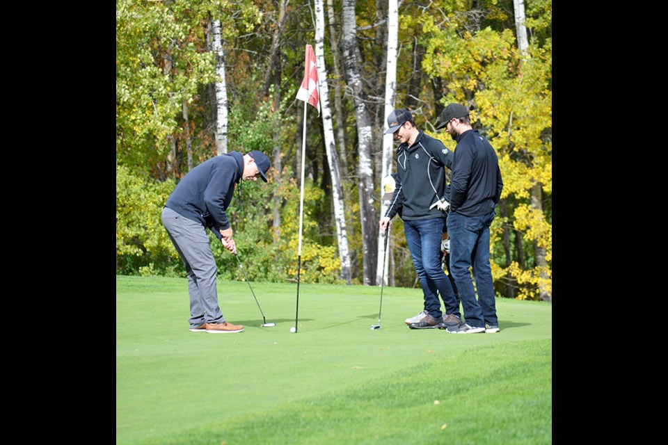 A golfer sinks a putt as 2 of his team mates look on during the 10th Annual Kenosee Lions Golf Tournament.