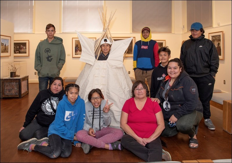 Students from Thunderchilld First Nation and their guardians pose for a picture with facilitator Diane Pooyak and the tipi they helped build according to ceremony.