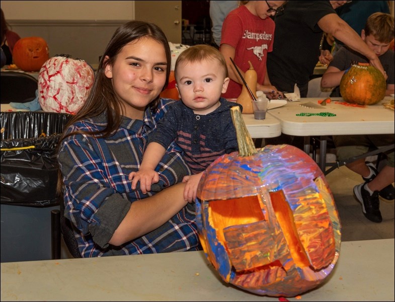 Avery Hrynewich and Teagan Poitras show off a carved pumpkin that is also colorfully painted.