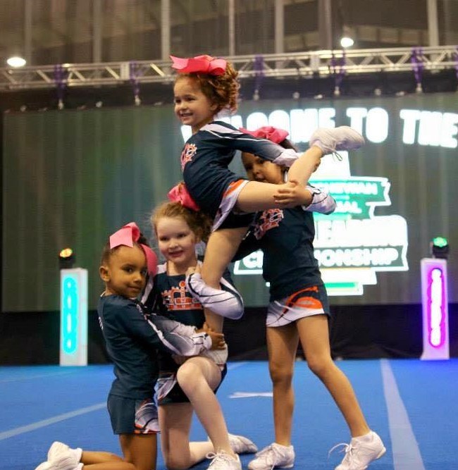 This photo shows a level 1 stunt group in competition where the flyer is supported by her bases in t