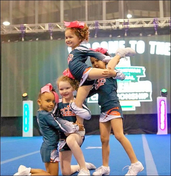 This photo shows a level 1 stunt group in competition where the flyer is supported by her bases in t