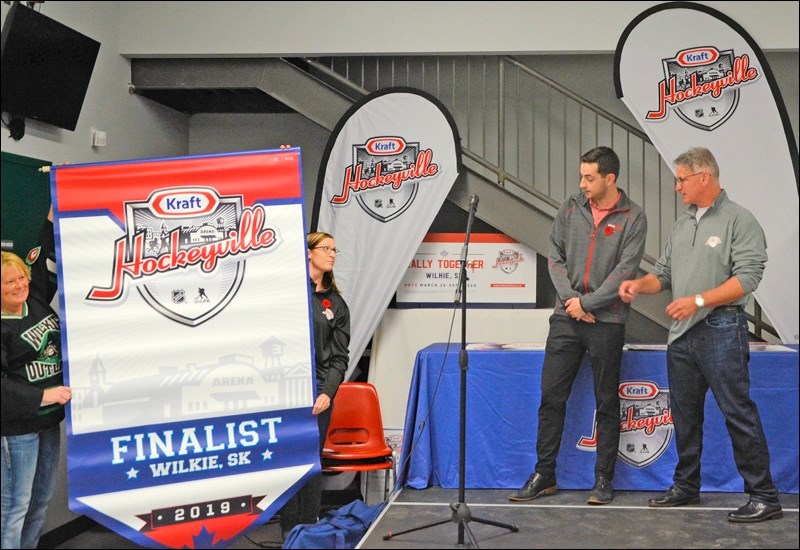 Wlkie’s Hockeyville campaign co-organizer, Helen Urlacher and recreation director Lori Fenrich show off the Kraft Hockeyville banner which will hang in the arena with provincial and league title banners. On stage are Rhett Kappel of Saskatoon, representing Kraft Heinz Canada, and Mike Sillinger, representing the National Hockey League Players’ Association. All photos by Helena Long