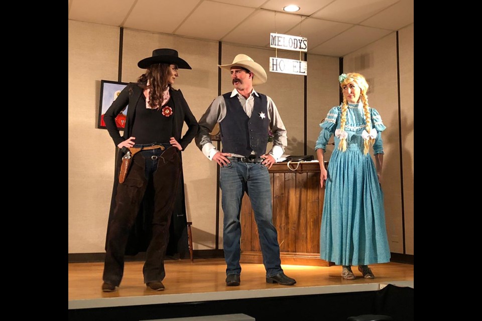 Ainsley Sauter as Wild Prairie Rose talking to Sheriff Billy Bold played by Kent Sauter while Moose Mountain Melody played by Jada Wright looks on worriedly.