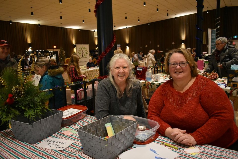 Lise Rochefort, left, and Audrey Savenkoff manned the entry table at the OCC Hall during the Christmas in November craft sale, taking names for the “door prize,” left, and selling tickets for the rainbow auction of prizes donated by the show vendors.