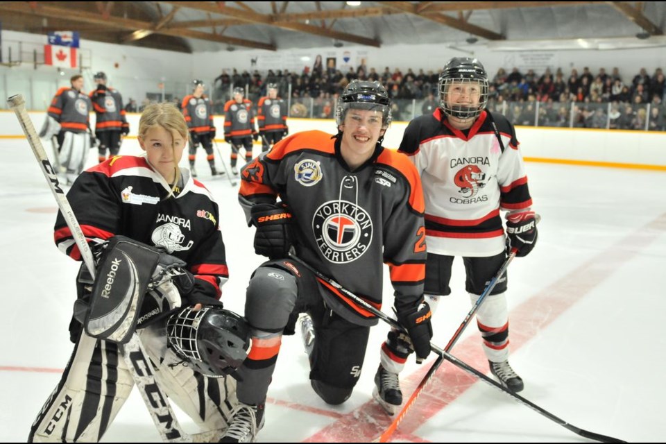 At the SJHL game between the Yorkton Terrier and the visiting Kindersley Klippers in Canora on November 30, Vaughn Wilgosh, who grew up playing for the Canora Cobras and is now a member of the Yorkton Terriers, posed for a photo with current Canora Cobras players Ty Northrup, atom goalie, and Logan Sznerch, peewee defenceman.